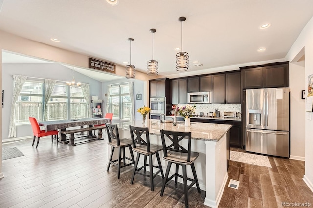 25128 E Maple Ave, Aurora, CO 80018 - kitchen with stainless steel appliances, dark brown cabinets, dark wood finished floors, light stone counters, and pendant lighting