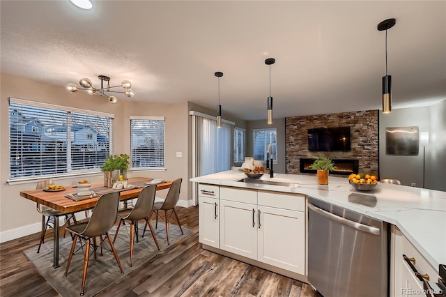 kitchen featuring hanging light fixtures, sink, stainless steel dishwasher, and white cabinets