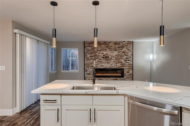 kitchen featuring hanging light fixtures, white cabinetry, sink, and stainless steel dishwasher