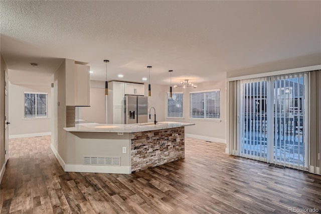 kitchen featuring sink, stainless steel fridge, dark wood-type flooring, white cabinetry, and decorative light fixtures