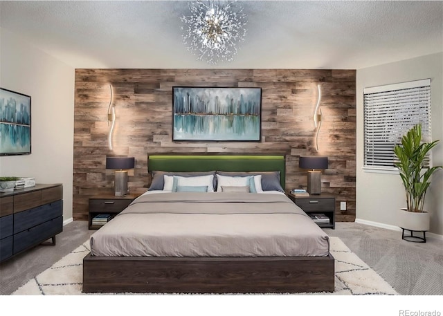 bedroom featuring an inviting chandelier, light colored carpet, a textured ceiling, and wood walls