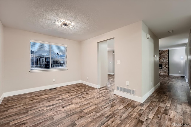 empty room with hardwood / wood-style floors, a fireplace, and a textured ceiling