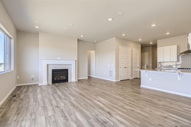 unfurnished living room featuring a fireplace, light hardwood / wood-style flooring, and sink