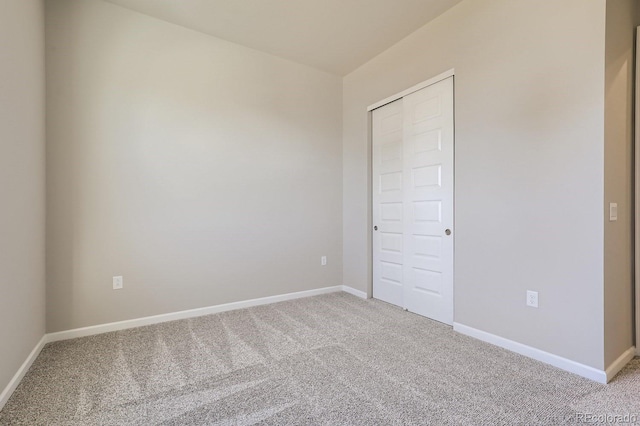 unfurnished bedroom with light colored carpet and a closet