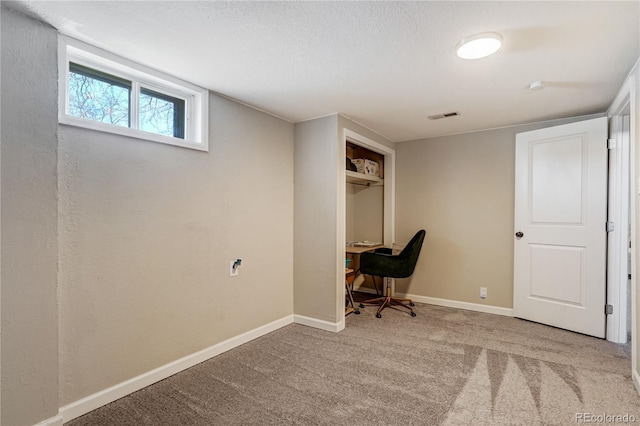 unfurnished office featuring carpet, visible vents, a textured ceiling, and baseboards