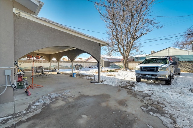 snowy yard with a patio area and fence