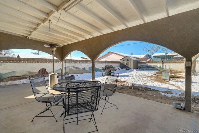 view of patio / terrace with outdoor dining area, a fenced backyard, an outdoor structure, and a shed