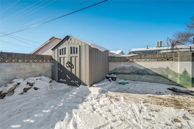 snow covered structure featuring a shed, an outdoor structure, and a fenced backyard