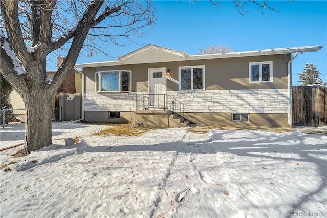 single story home featuring stone siding, fence, and stucco siding