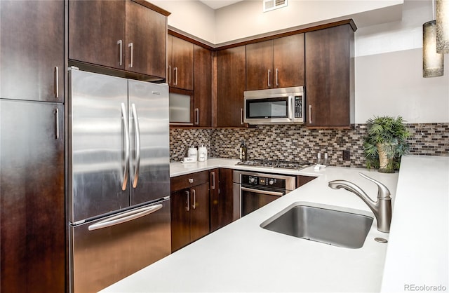 kitchen with stainless steel appliances, sink, backsplash, and dark brown cabinets