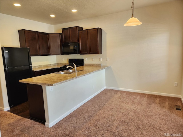 kitchen with a peninsula, a sink, hanging light fixtures, light countertops, and black appliances