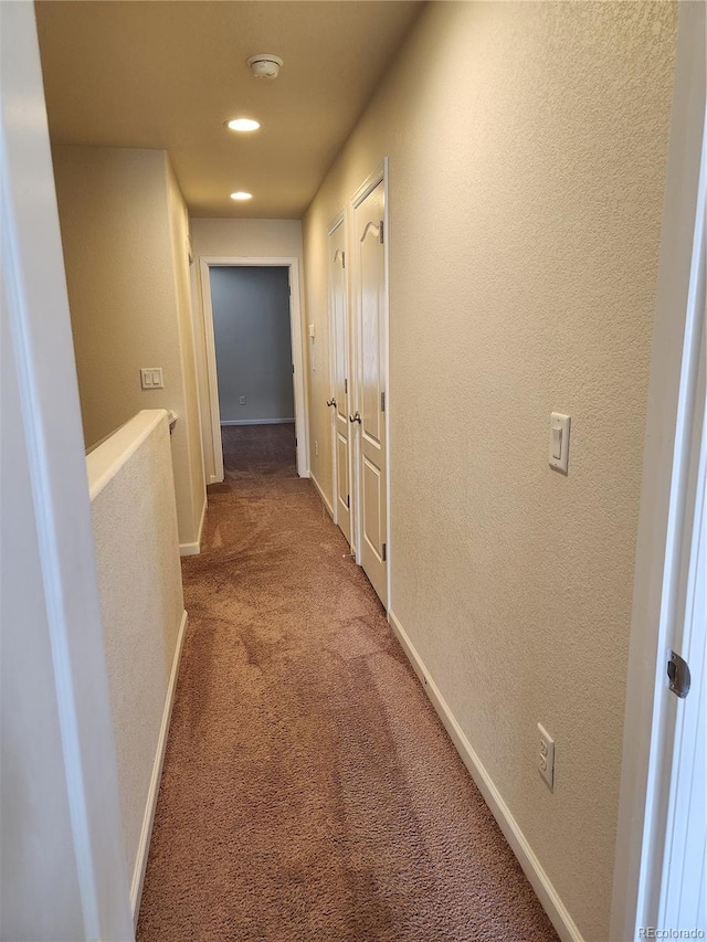 hallway with recessed lighting, carpet, baseboards, and a textured wall