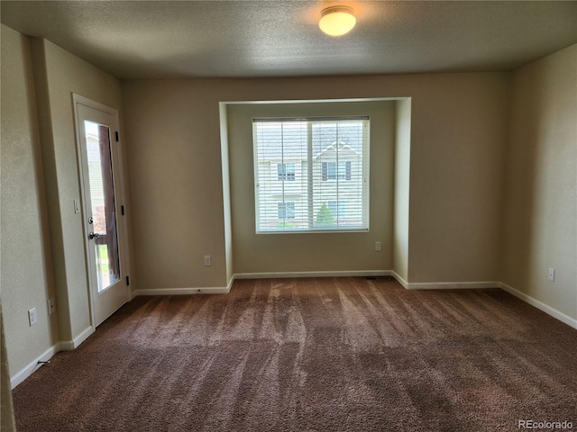 unfurnished room with a textured ceiling, dark colored carpet, baseboards, and a healthy amount of sunlight