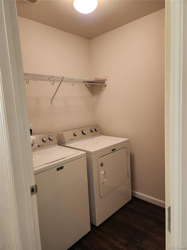 washroom with laundry area, washing machine and clothes dryer, dark wood finished floors, and baseboards