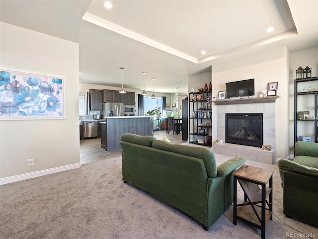 living room featuring baseboards, a tray ceiling, recessed lighting, and light colored carpet