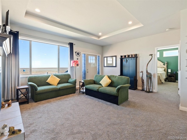 carpeted living area with baseboards, a tray ceiling, and recessed lighting