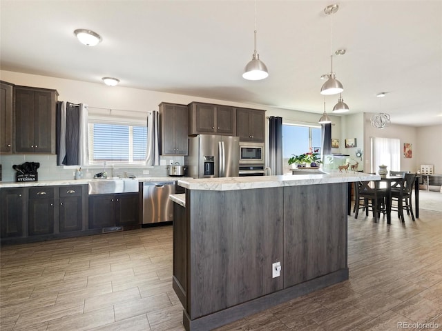 kitchen featuring light countertops, appliances with stainless steel finishes, a healthy amount of sunlight, a sink, and dark brown cabinetry