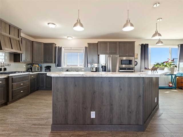 kitchen featuring appliances with stainless steel finishes, pendant lighting, dark brown cabinetry, and decorative backsplash