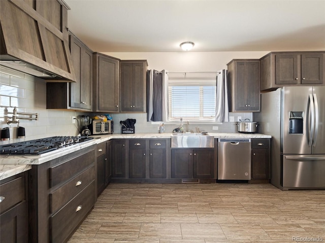 kitchen with backsplash, appliances with stainless steel finishes, dark brown cabinets, and a sink