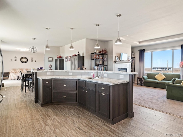 kitchen with open floor plan, a tile fireplace, a sink, and dark brown cabinetry