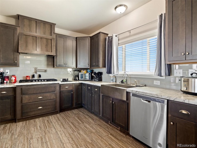 kitchen featuring dark brown cabinetry, a sink, vaulted ceiling, appliances with stainless steel finishes, and backsplash