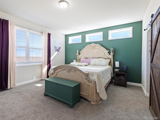 carpeted bedroom with baseboards and a barn door