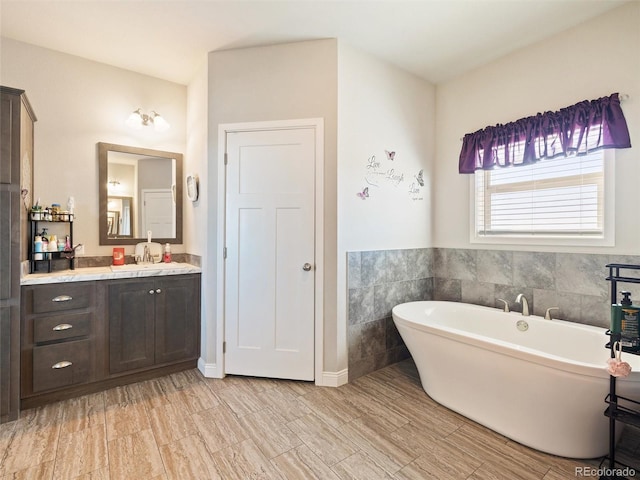 full bath with a soaking tub, tile walls, and vanity