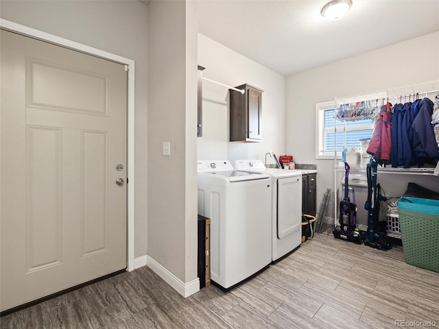 laundry area with light wood-style floors, washer and dryer, cabinet space, and baseboards