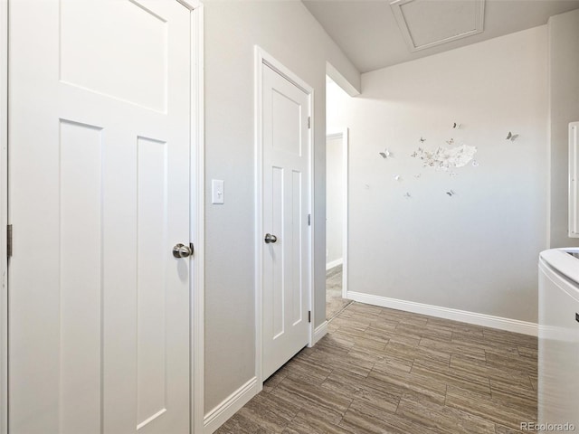 corridor featuring attic access, baseboards, and wood finished floors