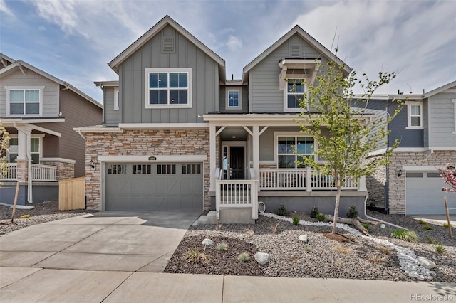 craftsman inspired home with an attached garage, stone siding, board and batten siding, a porch, and driveway