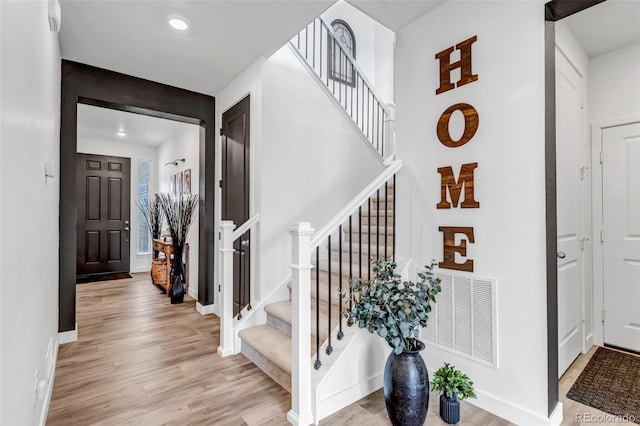 stairs with baseboards, recessed lighting, wood finished floors, and visible vents