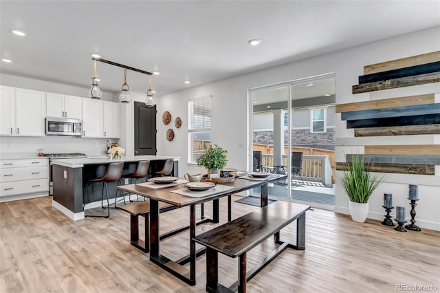 dining area with recessed lighting, light wood-style flooring, and a fireplace