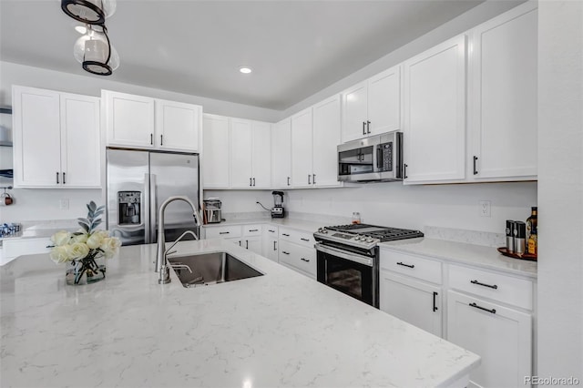 kitchen featuring light stone counters, a sink, white cabinetry, and appliances with stainless steel finishes
