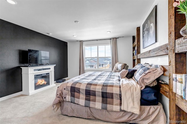 carpeted bedroom featuring a glass covered fireplace and recessed lighting