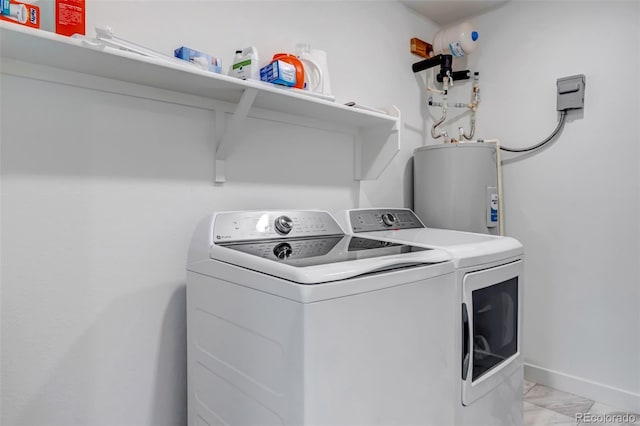 clothes washing area with laundry area, marble finish floor, baseboards, washer and clothes dryer, and electric water heater