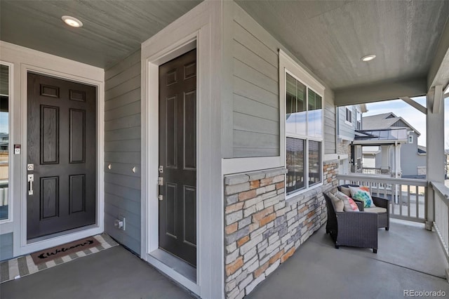 doorway to property featuring covered porch and stone siding
