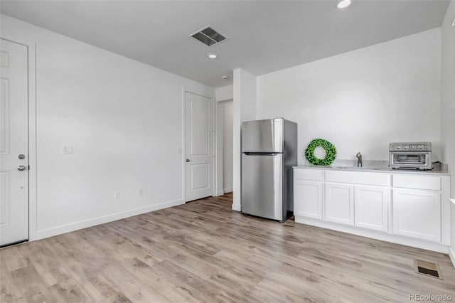 kitchen featuring visible vents, freestanding refrigerator, and light wood finished floors