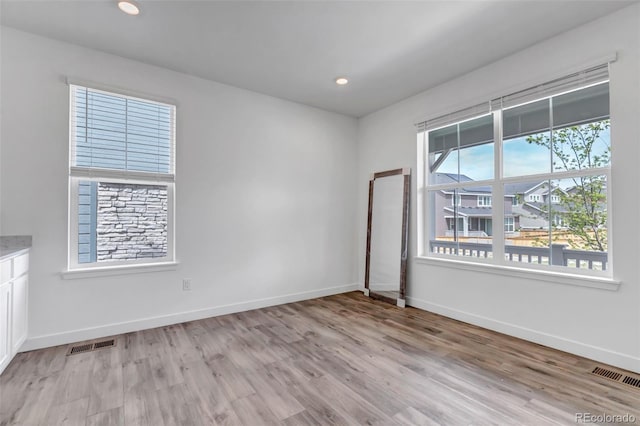 spare room featuring baseboards, light wood finished floors, and visible vents