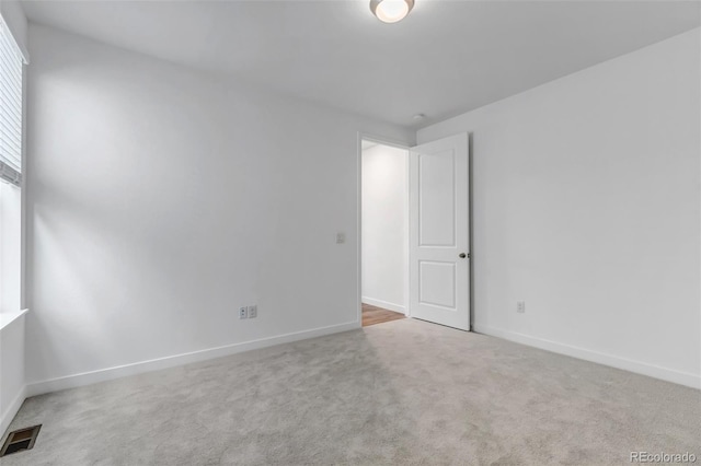 carpeted spare room with visible vents and baseboards
