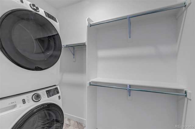 laundry room featuring laundry area, stacked washing maching and dryer, and baseboards