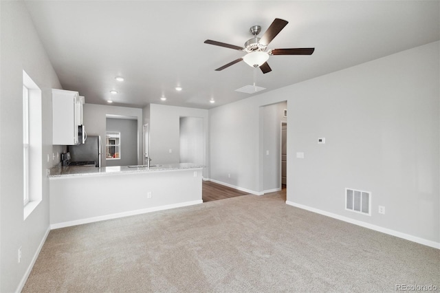 unfurnished living room with ceiling fan, sink, and carpet floors