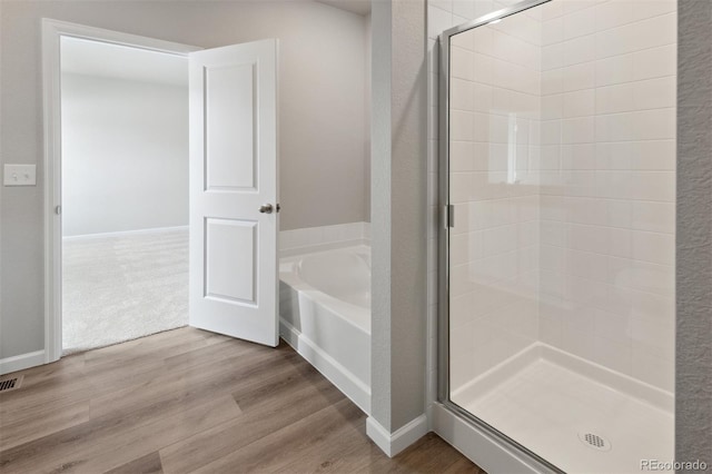 bathroom featuring hardwood / wood-style flooring and plus walk in shower