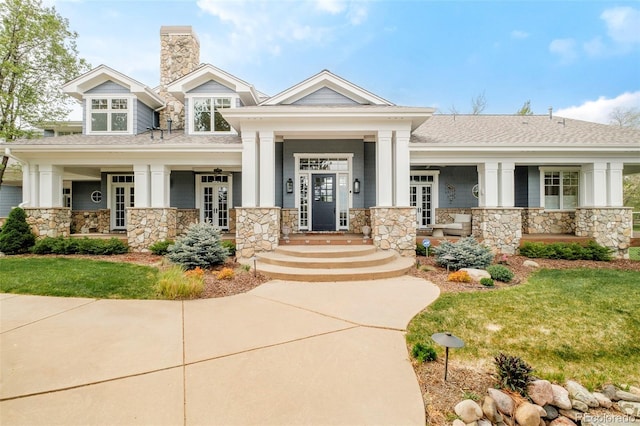 5425 S University Blvd, Greenwood Village, CO 80121 - view of front facade with stone siding, a chimney, roof with shingles, and a porch