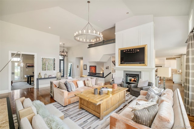 5425 S University Blvd, Greenwood Village, CO 80121 - living area with light wood-type flooring, high vaulted ceiling, a glass covered fireplace, a chandelier, and baseboards
