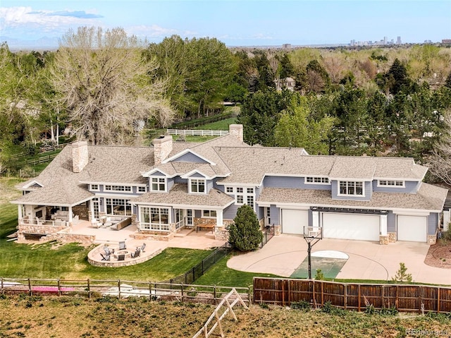 5425 S University Blvd, Greenwood Village, CO 80121 - rear view of house featuring a fenced backyard, concrete driveway, a patio, stone siding, and a garage