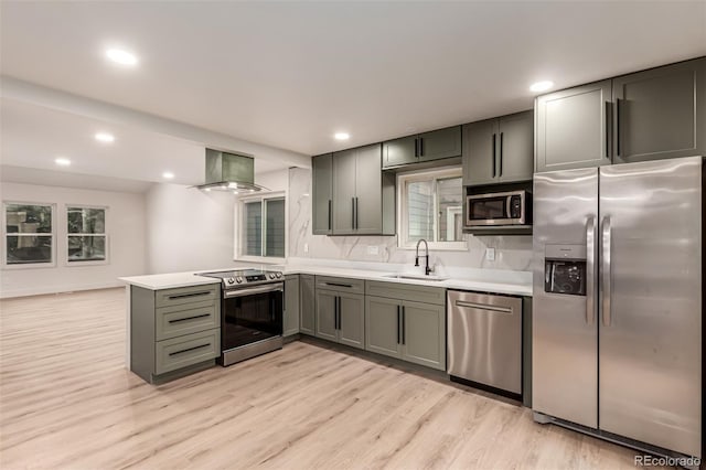 4714 S Simms Ct, Morrison, CO 80465 - kitchen featuring stainless steel appliances, wall chimney exhaust hood, light countertops, light wood-style floors, and a peninsula