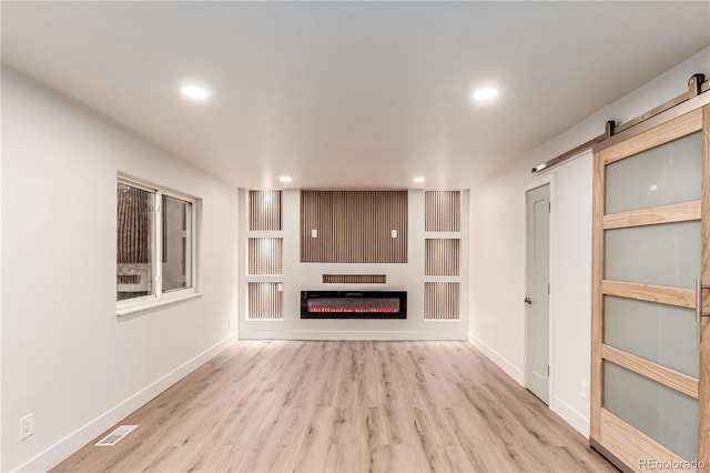 4714 S Simms Ct, Morrison, CO 80465 - unfurnished living room with recessed lighting, wood finished floors, a barn door, a glass covered fireplace, and built in features