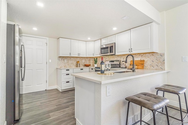 18751 E Mexico Ave, Aurora, CO 80017 - kitchen with stainless steel appliances, a peninsula, backsplash, light wood-style flooring, and white cabinets
