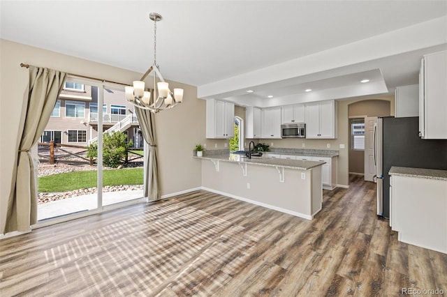 8216 Mahogany Wood Ct, Colorado Springs, CO 80927 - kitchen with stainless steel appliances, a chandelier, a kitchen breakfast bar, white cabinetry, and a peninsula
