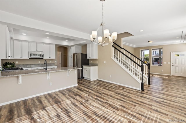 8216 Mahogany Wood Ct, Colorado Springs, CO 80927 - kitchen with stainless steel appliances, a chandelier, a sink, a breakfast bar area, and a peninsula